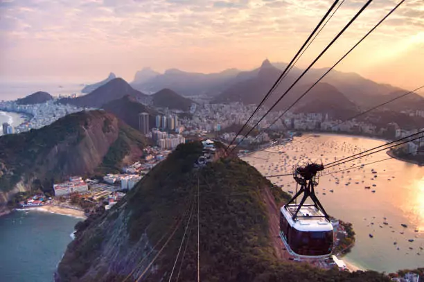 Sugarloaf Cable Car (Bondinho do Pao de Acucar) moving between Praia Vermelha and the Sugarloaf Mountain during sunnet