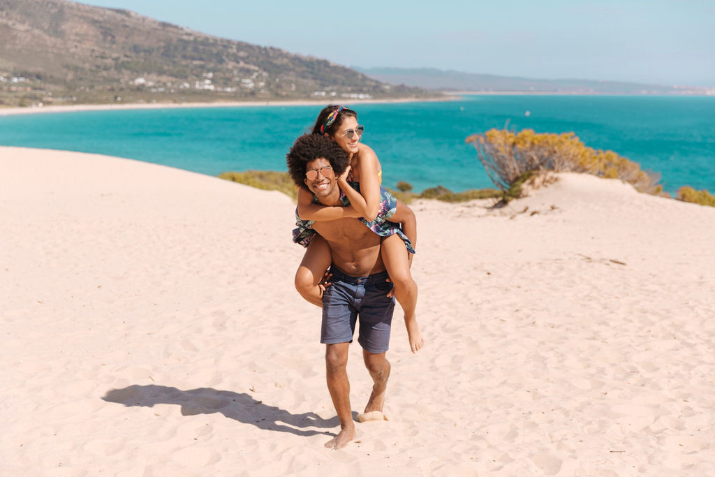 homem carregando mulher nas costas em passeio romântico em praia do rio de janeiro